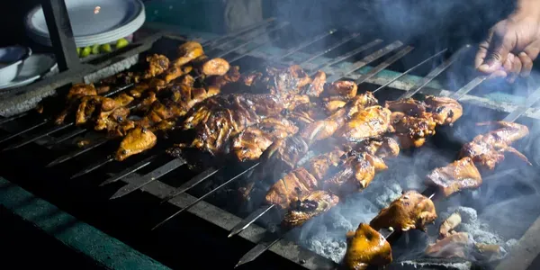 Smoky grilled chicken pieces on charcoal grill